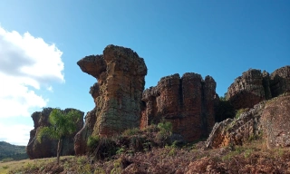 Formações rochosas que se assemelham a grandes torres acompanhadas de vegetação com destaque para ceu azul com poucas nuvens
