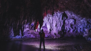 Silhueta de homem em interior de gruta. Se destaca a cor roxa.