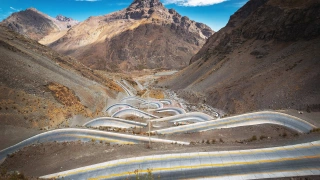 Estrada serpentina vista de cima e adornada pela imponente Cordilheira dos Andes