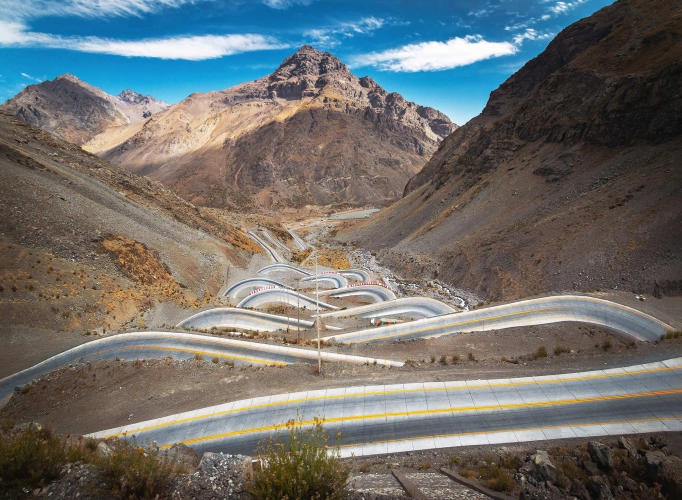 Estrada serpentina vista de cima e adornada pela imponente Cordilheira dos Andes