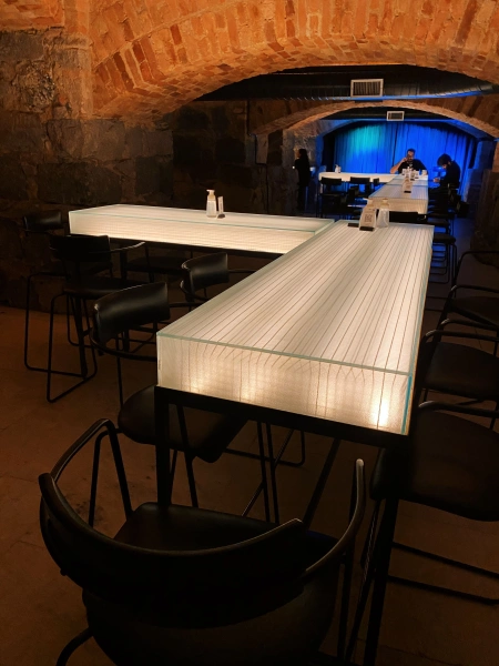 Mesa iluminada de um bar subterrâneo com paredes de tijolos expostos