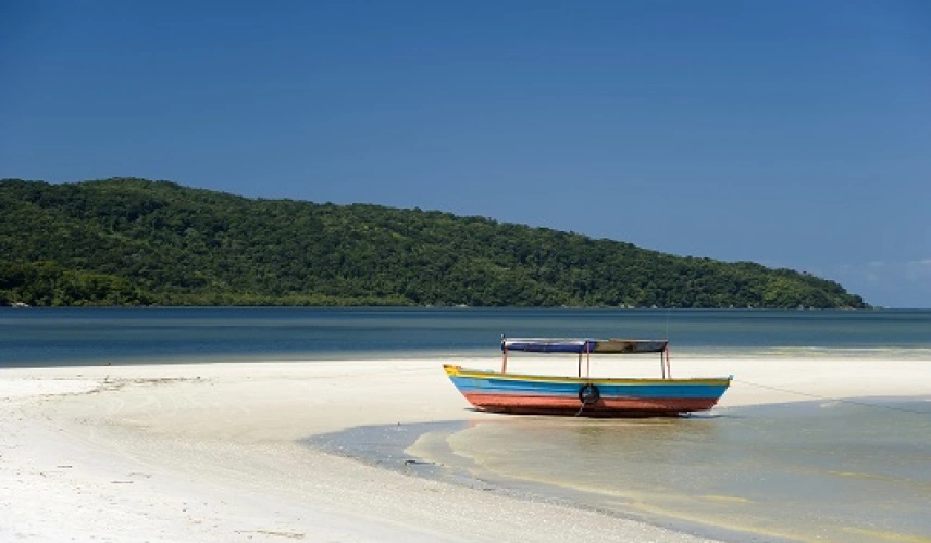 Barco estacionado em areias claras de praia deserta em dia ensolarado