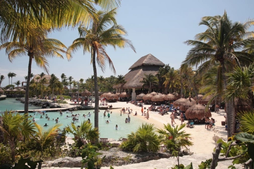 Vista de hotel caribenho com muitos turistas em frente ao mar. A natureza local se destaca.