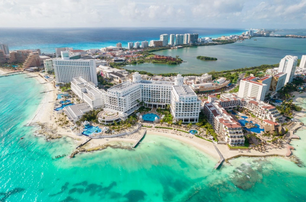 Vista de belos hotéis na zona hoteleira de Cancún circundados por mar de cor verde translúcida e areia branca.