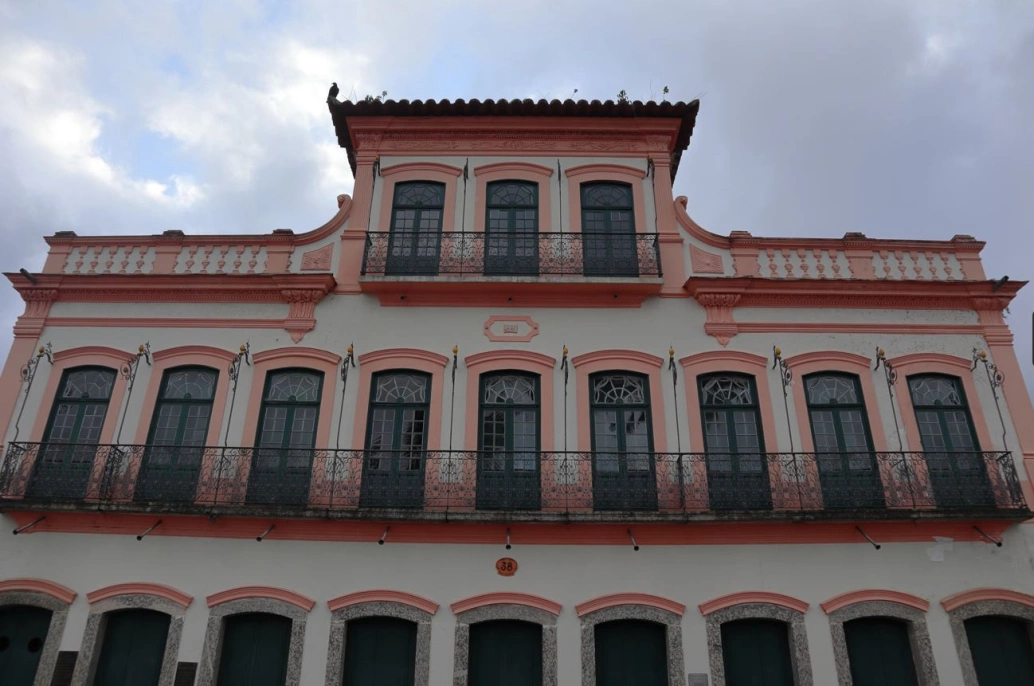 Vista frontal de um casarão colonial com três andares e janelas compridas