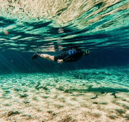 Homem flutuando sobre rio de água azul cristalina em dia claro