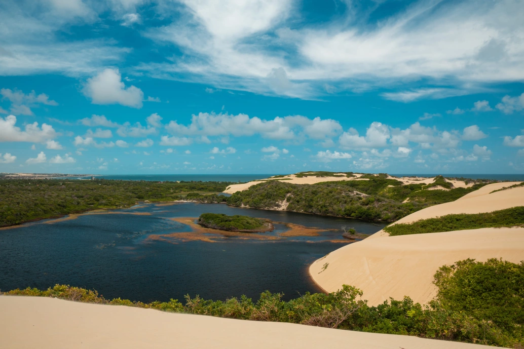 Vista deslumbrante de lagoa envolta de areia branca e vegetação tropical.