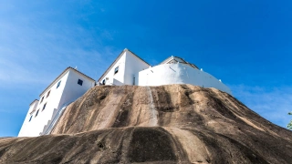 Um convento pintado de branco construído sob uma enorme pedra