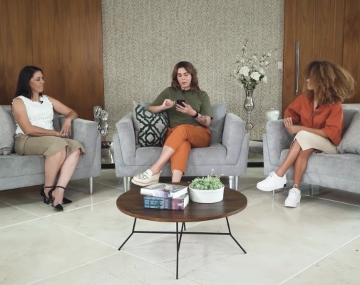 Três mulheres sentadas em sofá reunidas em sala