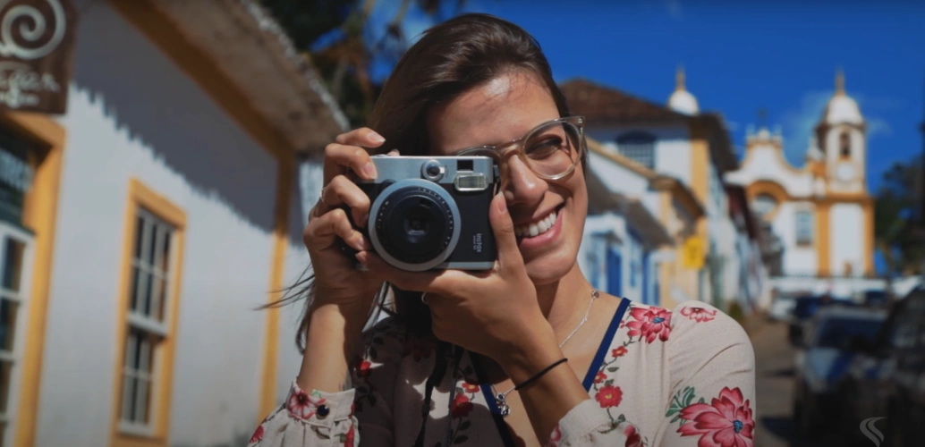 Garota sorrindo com câmera fotográfica em mãos