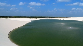 Lagoa de cor esverdeada, contornada por dunas de areia branca