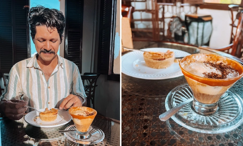 À esquerda, um homem sentado à mesa aprecia um café da tarde. À direita, um close do prato que ele está comendo com um salgado recheado e um café cremoso.