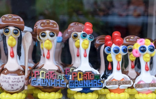 Várias pequenas esculturas de galinhas coloridas reunidas com dizeres de Porto de Galinhas, o famoso destino turístico de Pernambuco.