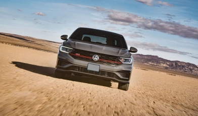 Frente de um Volkswagen Jetta 2020 em movimento em um deserto com montanhas ao fundo.