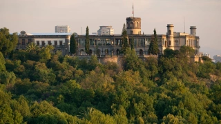 Bosque histórico em meio ao verde da natureza. Um castelo acima se destaca.