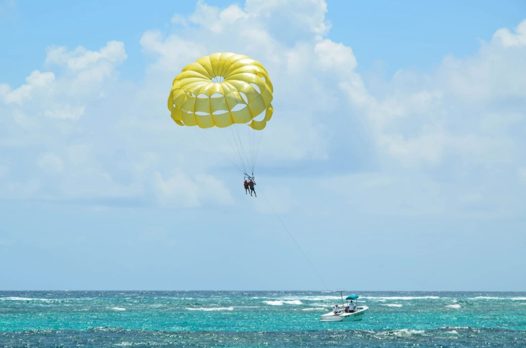Paraquedas com dois passageiros sendo puxado por um barco sobre o oceano em Punta Cana