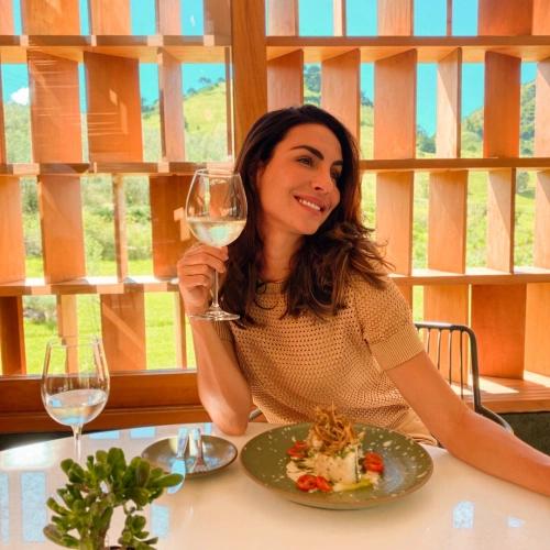 Mulher segura taça de vinho branco durante refeição em restaurante ao ar livre