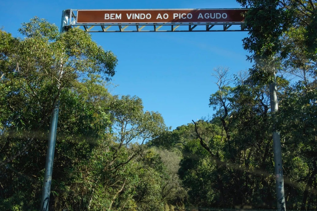 Foto placa de sinalização rodoviária com os dizeres: “Bem-vindo ao Pico Agudo” na entrada do Pico Agudo em Santo Antonio Pinhal.