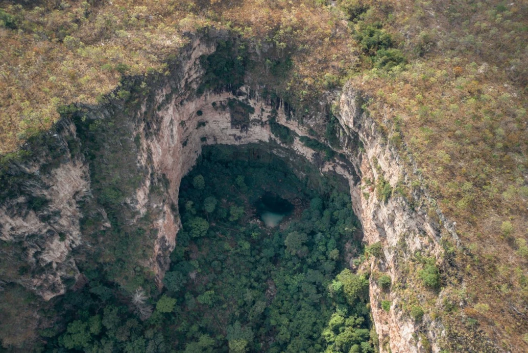 Vista aérea de um grande cânion com um nascente no meio de uma área de floresta em Barra do Garças, MT.