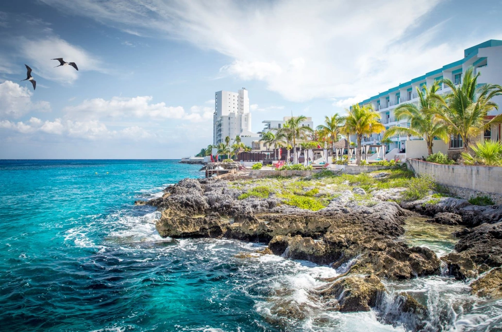 Vista de ilha com infraestrutura de hotéis banhada por mar caribenho de cor azul.