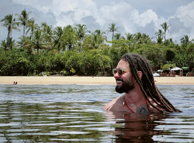 Músico Gabriel Elias sorrindo mergulha em rio em dia claro