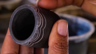 Artista do norte de Minas Gerais manipula pequeno utensílio artesanal de barro.