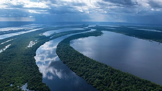 Vista aérea de um extenso rio cortado por vários caminhos de mata verde.