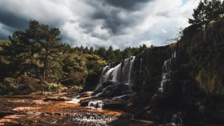 Paisagem da Cachoeira da Cabeceira localizada no Paraná. Águas da cachoeira caem pelas pedras cercas de vegetação nativa.
