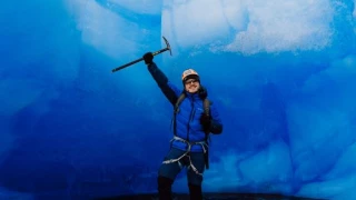 Homem com roupas de frio e equipamentos de trilha dentro de uma caverna de gelo na Patagônia chilena