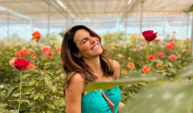 Mel Fronckowiak sorrindo dentro de jardim cheio de rosas