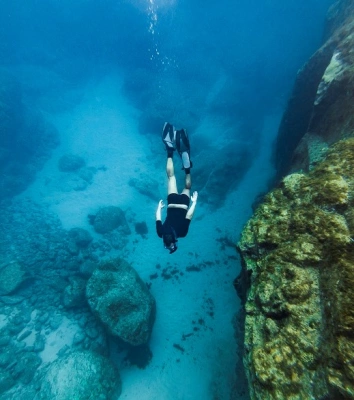 Uma pessoa mergulha nas profundezas do oceano em águas azuis cristalinas rodeada por corais