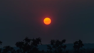Cair do dia no Cerrado brasileiro. Ao centro da foto, sol alaranjado se põe.