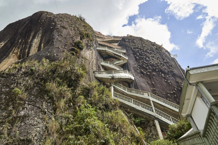 Vista de baixo da imponente rocha com um esquema de escadas em seu meio