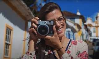Garota sorrindo com câmera fotográfica em mãos
