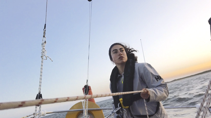 Tamara Klink segurando corda à beira de veleiro em alto mar