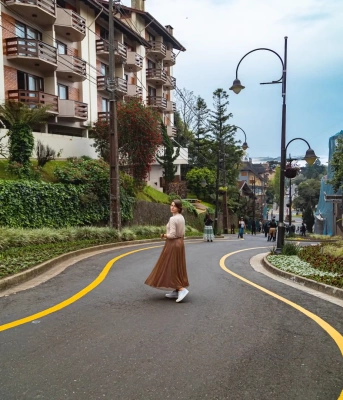 Mulher posa em rua turística com arquitetura europeia em dia ensolarado