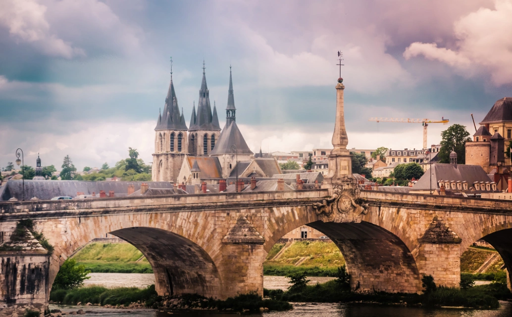 Ponte sobre o rio Loire, na França. Catedral e céu com nuvens ao fundo.