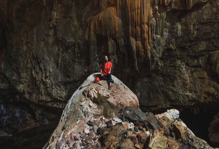 Mulher sentada em pedra da caverna de Terra Ronca em Goiás