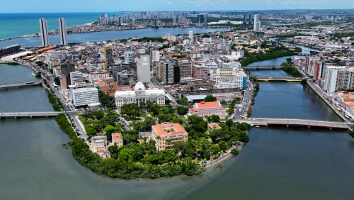 Vista aérea da cidade de Recife, cercada por um rio, por onde atravessam várias pontes