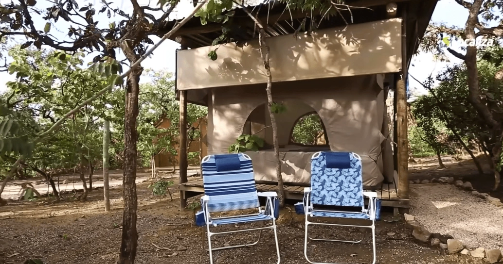 Hospedagem rústica em meio a região florestal com duas cadeiras de sol no quintal