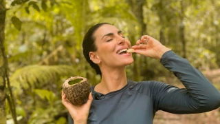 Mel Fronckowiak come fruta típica da Floresta Amazônica enquanto sorri.
