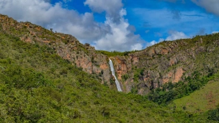 Queda d'água que se destaca em serra ao longo de vegetação que une Mata Atlântica e Cerrado.